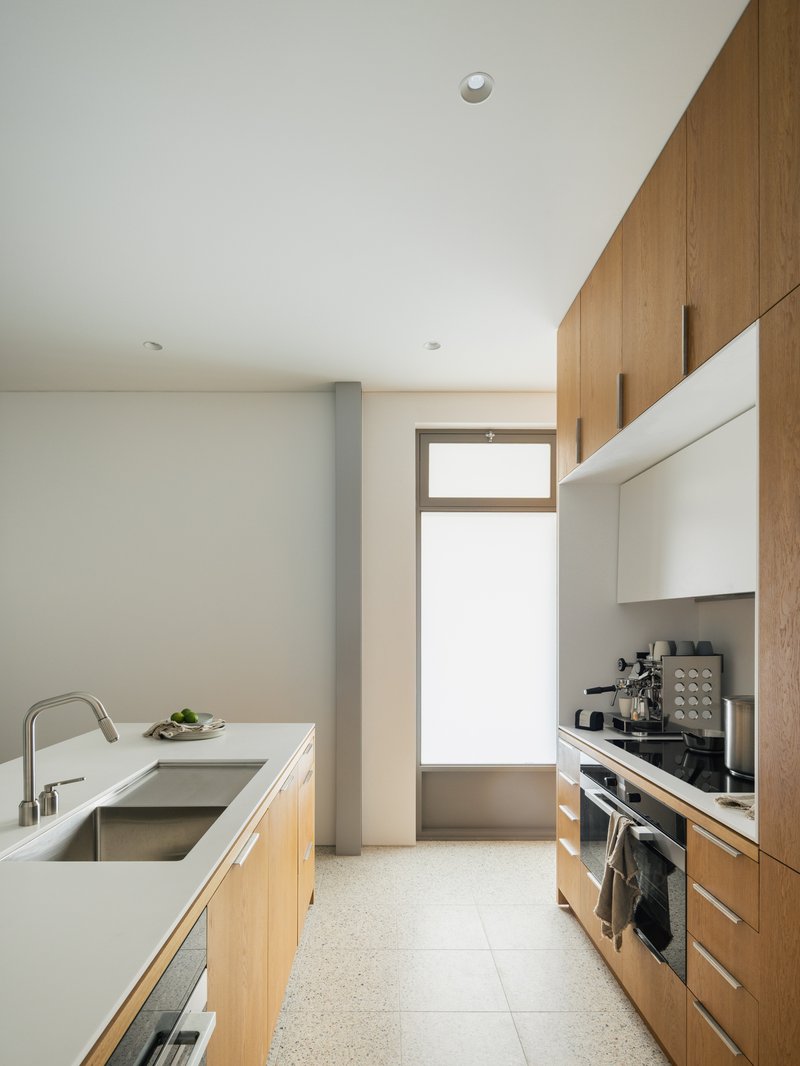 Galley kitchen with oak cabinetry and white countertop island under soft natural light