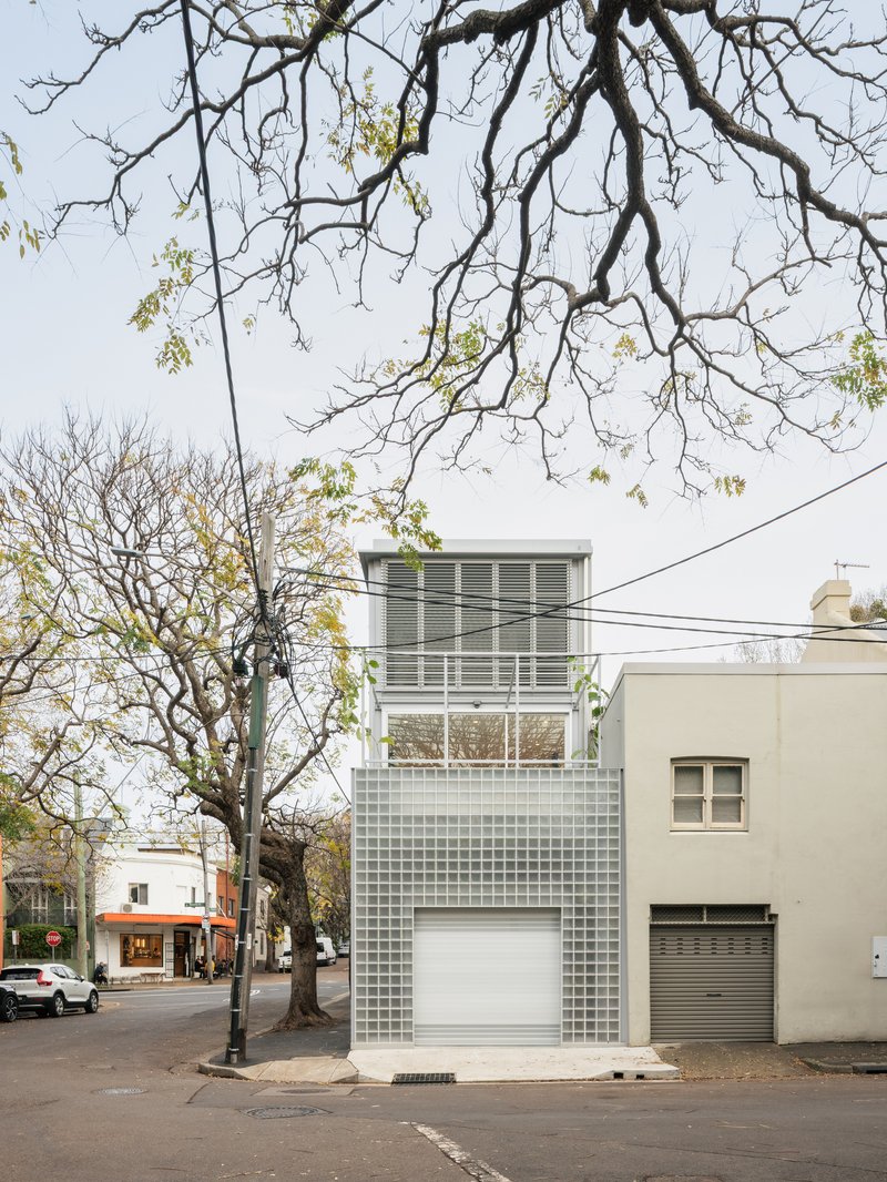 Front elevation showing stacked glass block volumes with louvered upper windows beneath bare branches