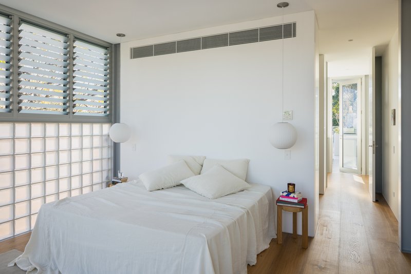 Bedroom with louvred window, glass block wall and recessed air conditioning grille above the bed