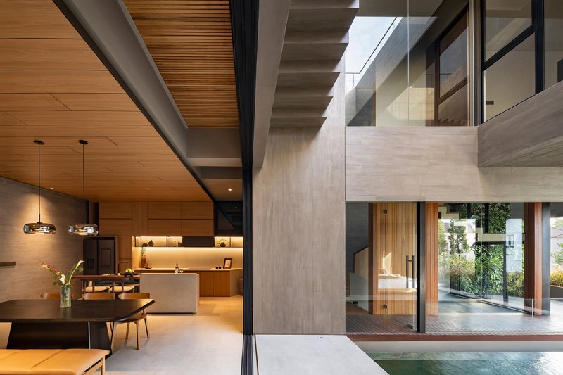 Open-plan living area with timber ceiling and views across pool to courtyard staircase