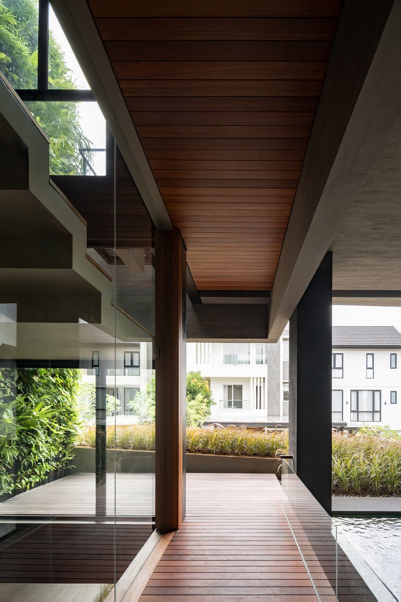 Covered timber deck with slat ceiling and glazed walls overlooking planted rooftop terrace and neighboring houses