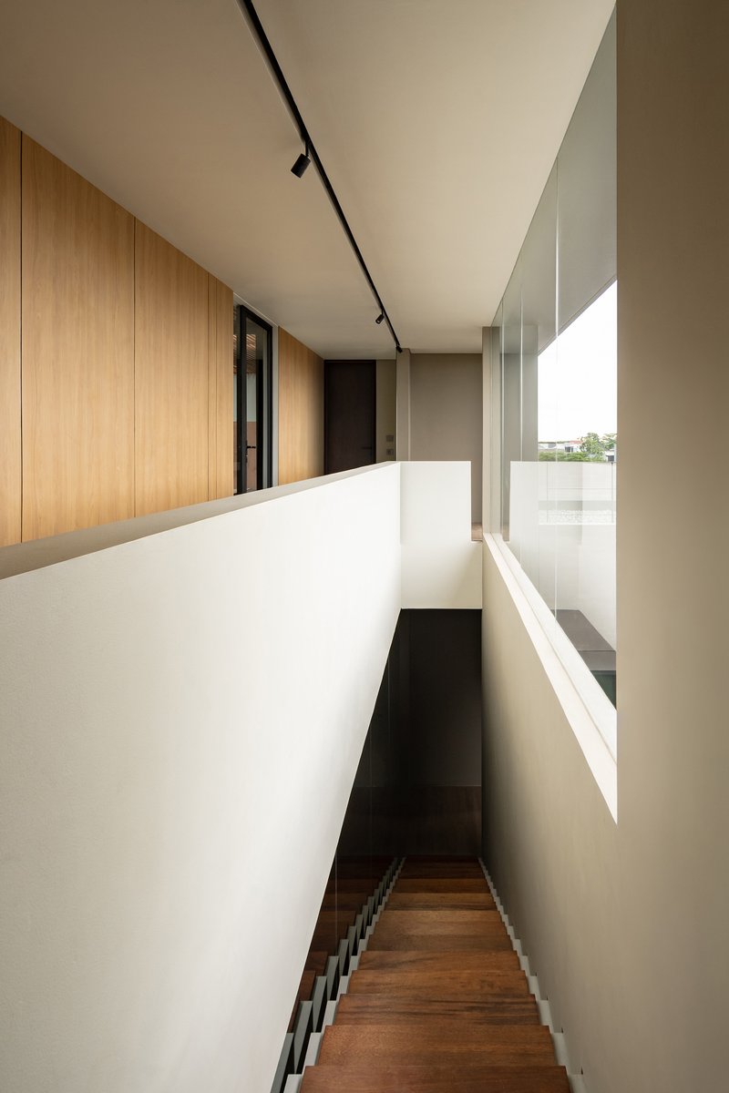 Upper-level hallway with white parapet wall and timber paneling overlooking stairwell with track lighting