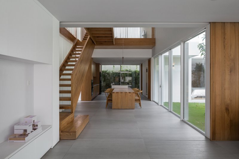 Double-height living space with timber staircase and mezzanine overlooking the dining area and garden courtyard