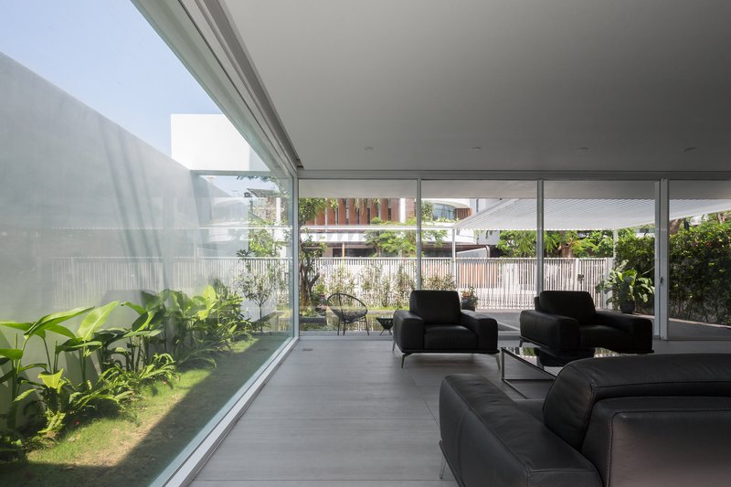 Living room with floor-to-ceiling glazing opening onto an internal planted courtyard with lawn