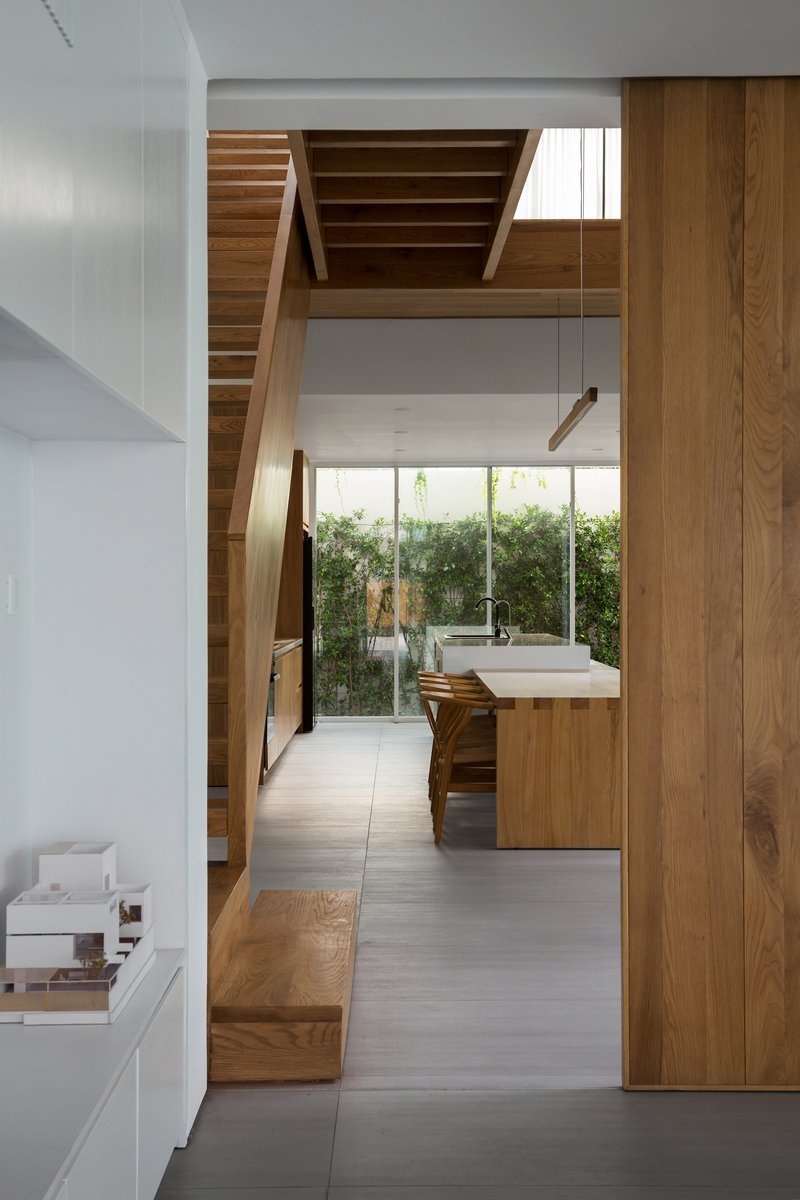 View through the stairwell toward the kitchen and garden courtyard beyond glass walls