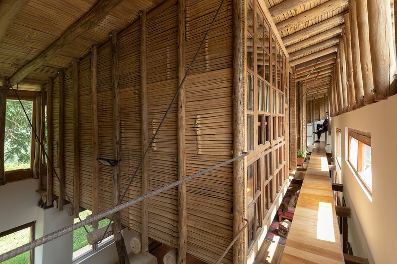 Narrow corridor with exposed bamboo slat ceiling and timber structural members alongside a white plastered wall