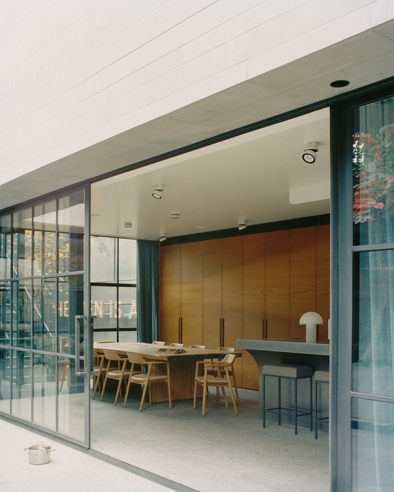 Sliding steel-framed glass doors opening onto a dining area with timber cabinetry and breakfast bar