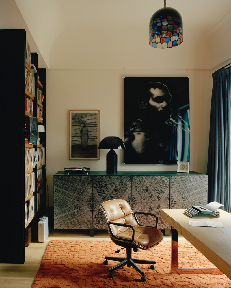Home office with patterned credenza beneath mosaic pendant light and tall bookshelves flanking the workspace