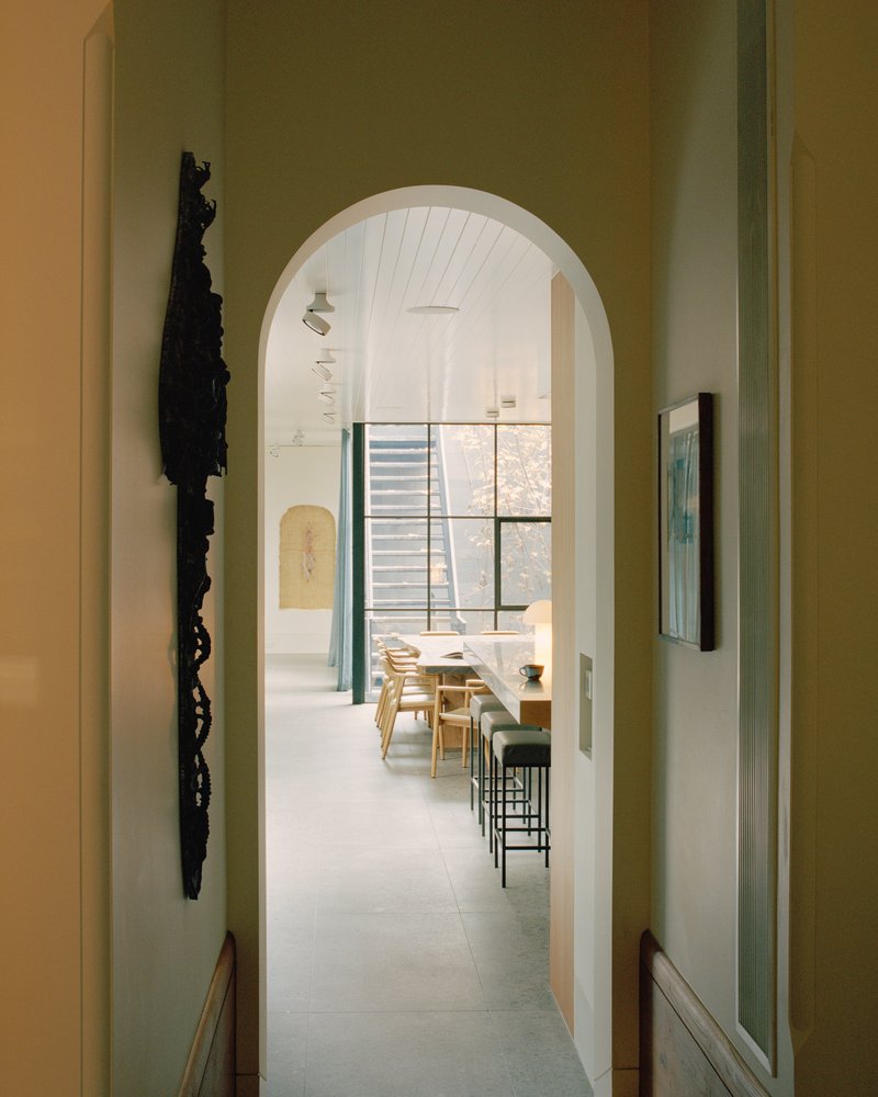 View through successive arched openings to dining space with gridded steel windows beyond
