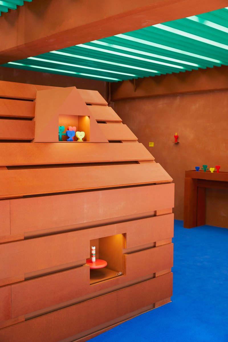 Corner view of stepped timber structure with square openings and colorful toys on shelves
