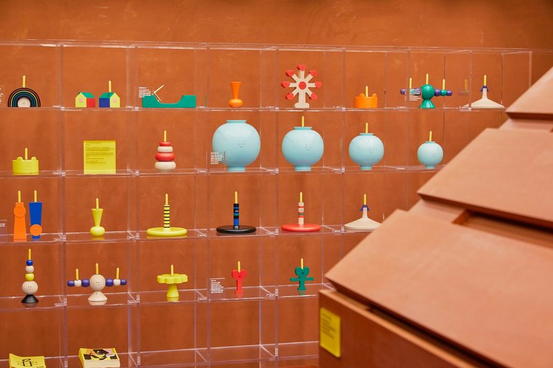 Clear acrylic display shelves holding colorful spinning tops against warm terracotta walls