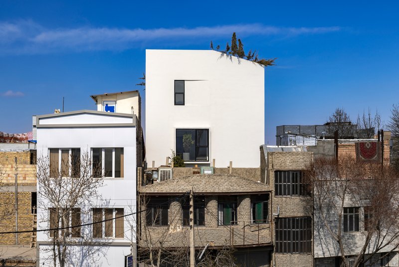 White tower rising above adjacent low brick buildings in a dense neighborhood under clear sky