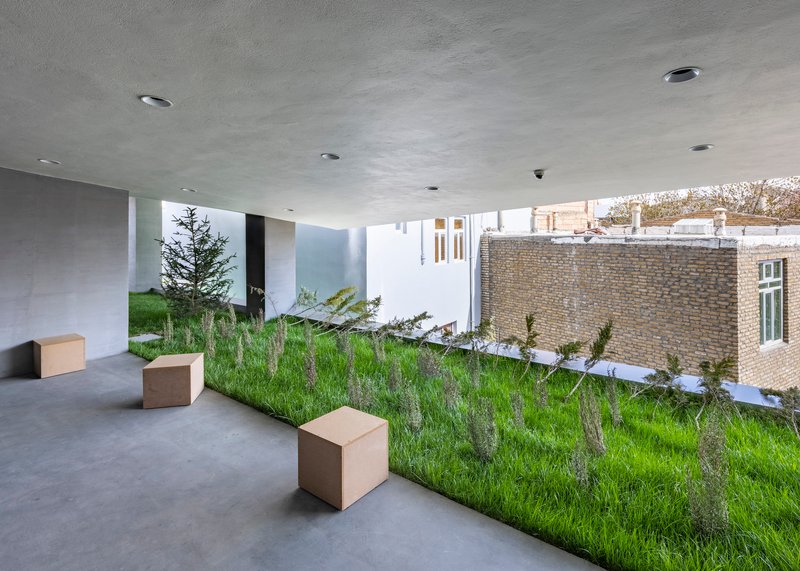 Gallery space with planted slope and cube benches beneath concrete ceiling and clerestory windows