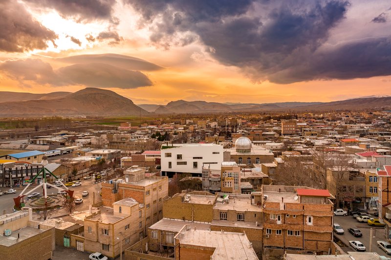 White cubic volume emerging from the urban fabric at sunset with mountains in the distance