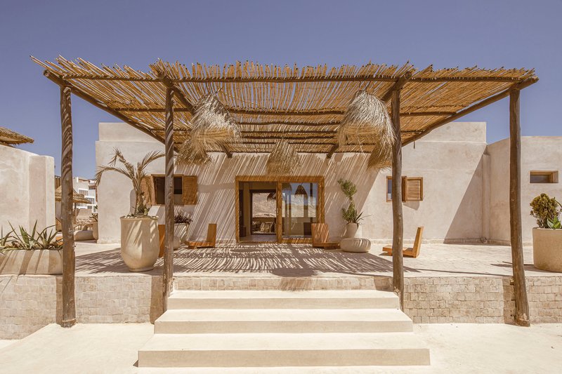 Covered terrace with timber posts, palm frond roof, and thatched pendants suspended over the glazed entrance doors