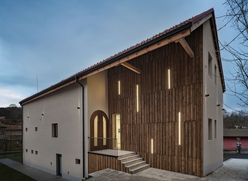 Vertical timber cladding with recessed strip lighting at the entrance volume at dusk