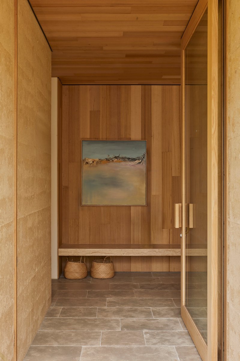 Entry vestibule with timber-lined walls and ceiling leading to a bench with woven baskets below