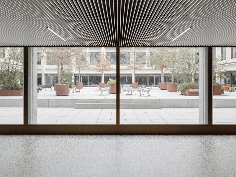 Interior view through bronze-framed glazing overlooking the courtyard with slatted wood ceiling overhead