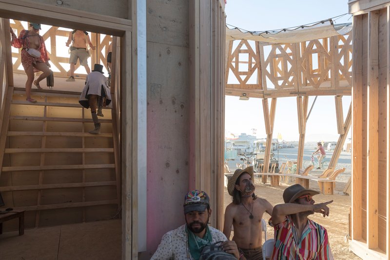 Timber staircase and elevated platform with geometric patterned screens, visitors climbing and gathering below