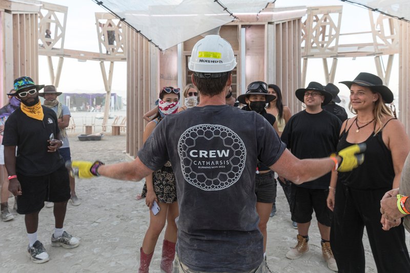 Interior gathering space with timber frame structure and fabric ceiling during a guided tour