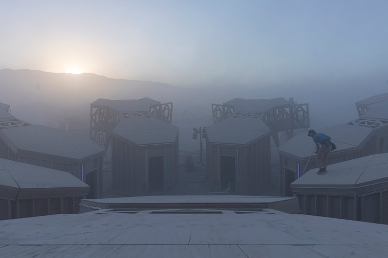 View of symmetrical timber structures with ornamental roof elements and a lone figure in heavy fog