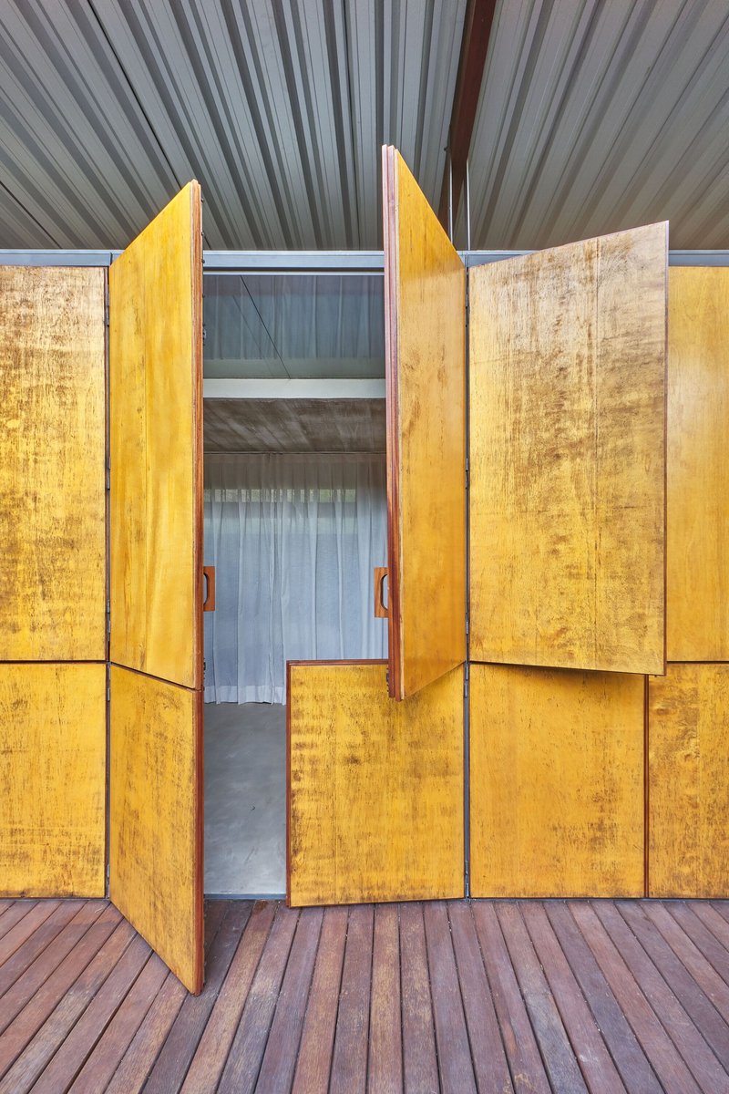 Central plywood doors swung open showing interior space and ribbed metal ceiling above timber deck