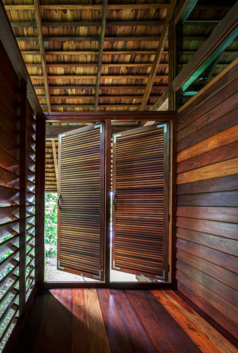 Timber hallway with horizontal slat shutters opening outward under a tiled pitched roof