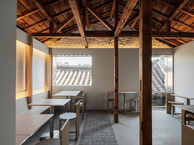 Seating area with timber columns, original roof structure, and windows to neighboring tile roofs