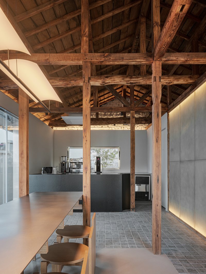 Cafe counter with dark timber seating beneath preserved timber columns and a coffered wooden ceiling structure