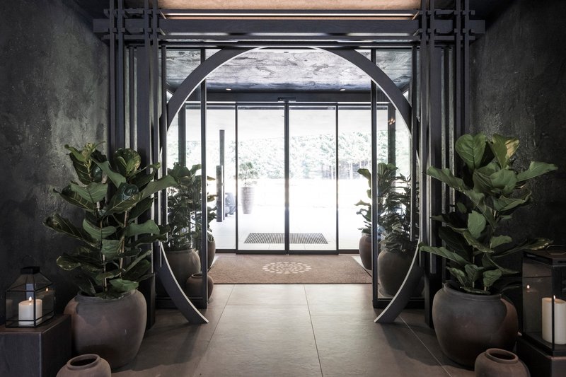 Entry foyer with octagonal steel portal frame flanked by potted plants and candlelit alcoves