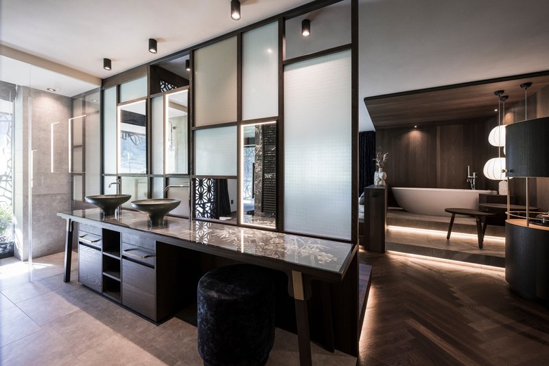 Double vanity with vessel sinks set against translucent glass partition panels framed in dark metal