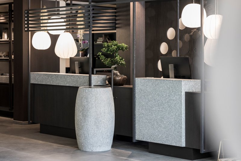 Freestanding terrazzo basin beside counters clad in matching stone with pendant lighting above