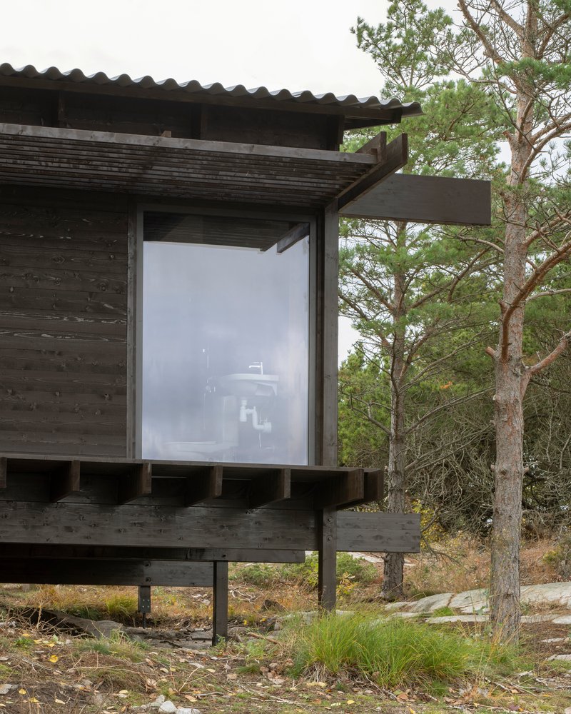 Corner window detail with blackened timber cladding and deep overhang supported by exposed timber posts
