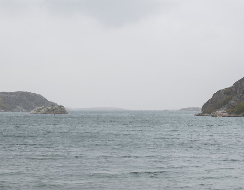 View across grey water toward rocky islands under overcast sky