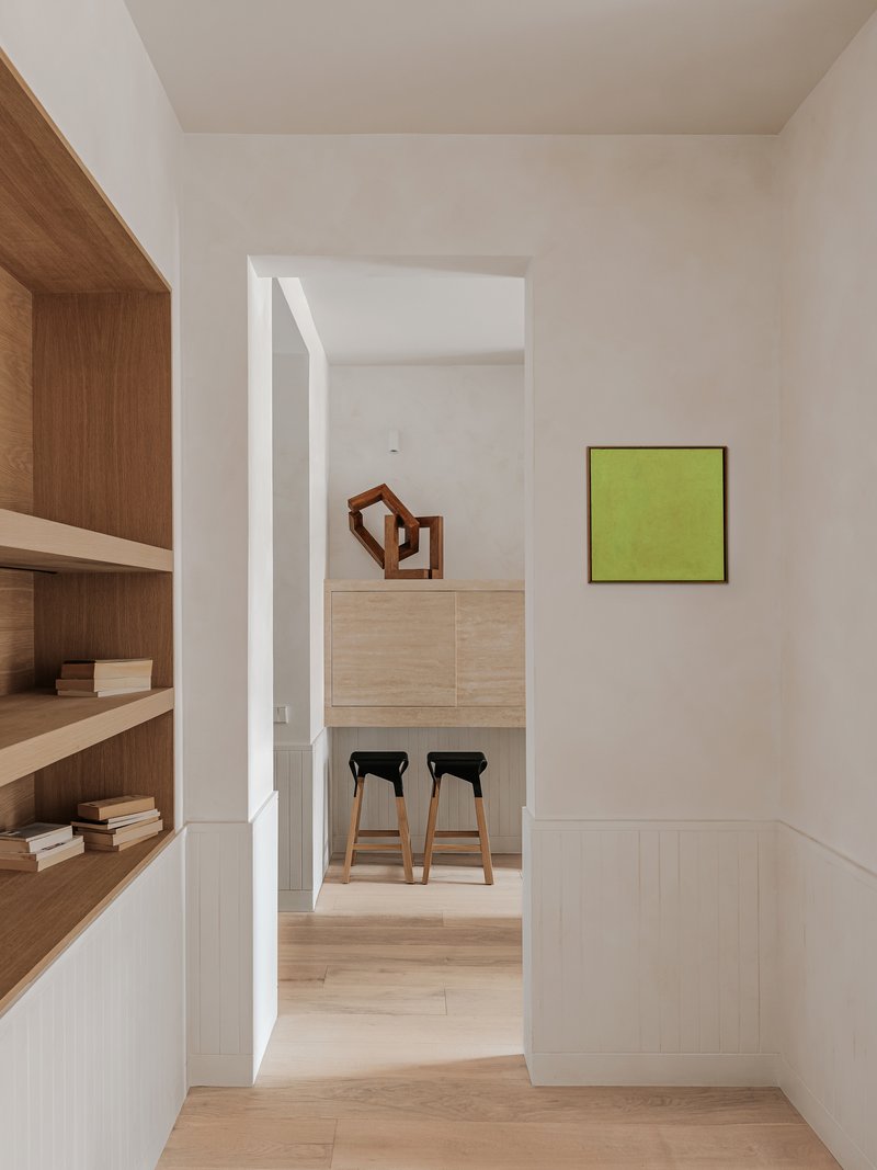 View through doorway to kitchen island with two bar stools and chartreuse painting on wall