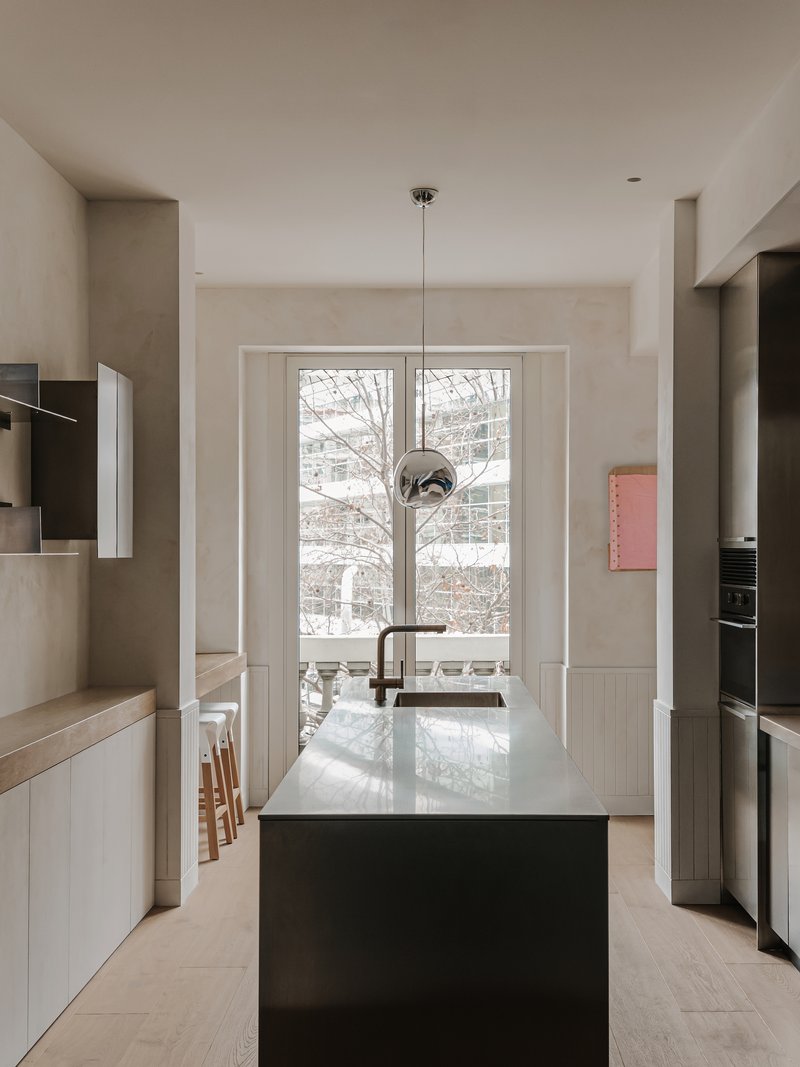Kitchen with black island, pendant light, and tall windows framing leafless branches outside