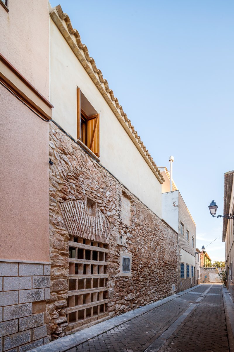 Street facade showing terracotta brick grate set into exposed stone wall beneath smooth white upper story
