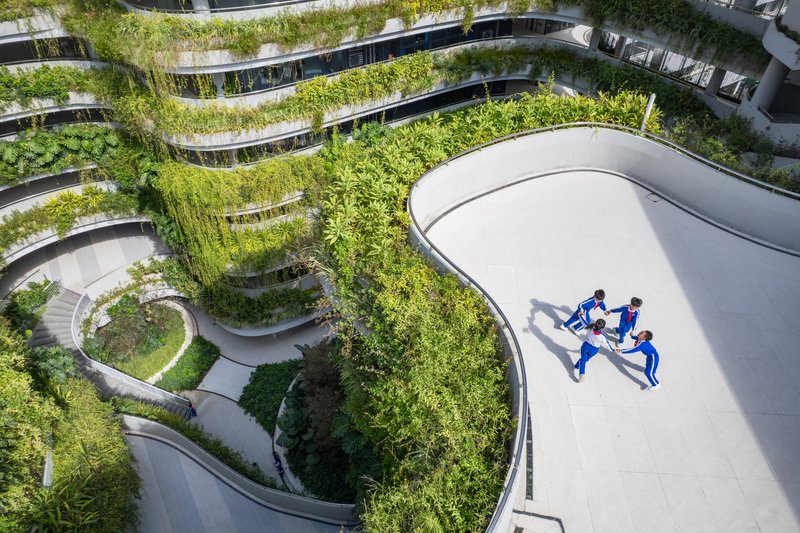 Aerial view of curving pathways and planted terraces with two runners crossing a white paved surface