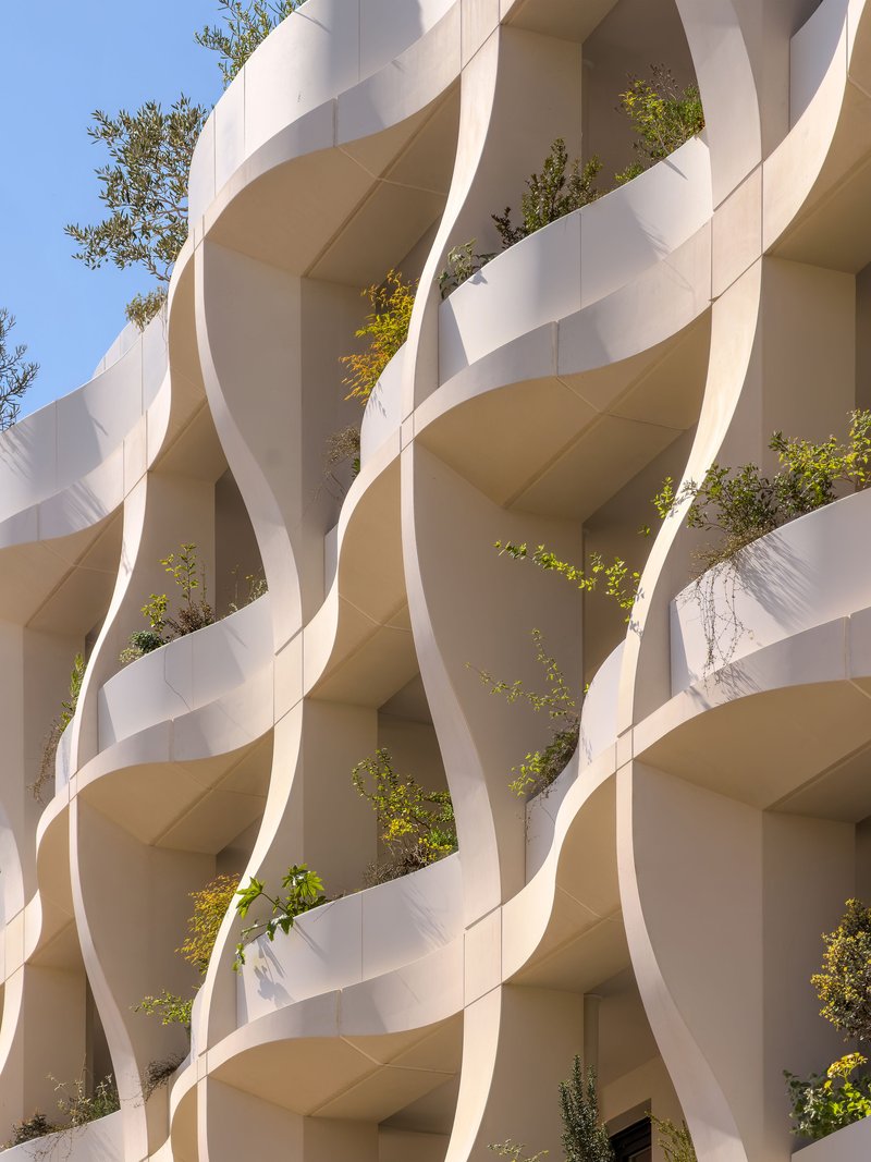 Detail of the ribbon-like balcony screens wrapping around planted recesses in bright daylight
