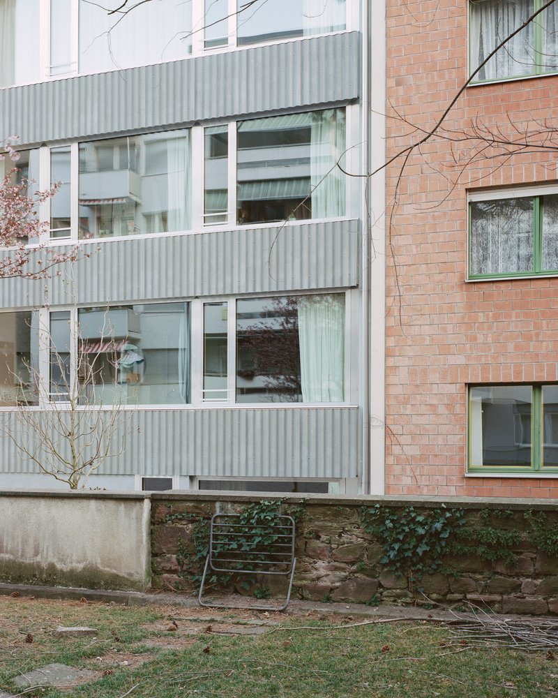 Corrugated metal facade with white window frames next to brick cladding and bare winter branches