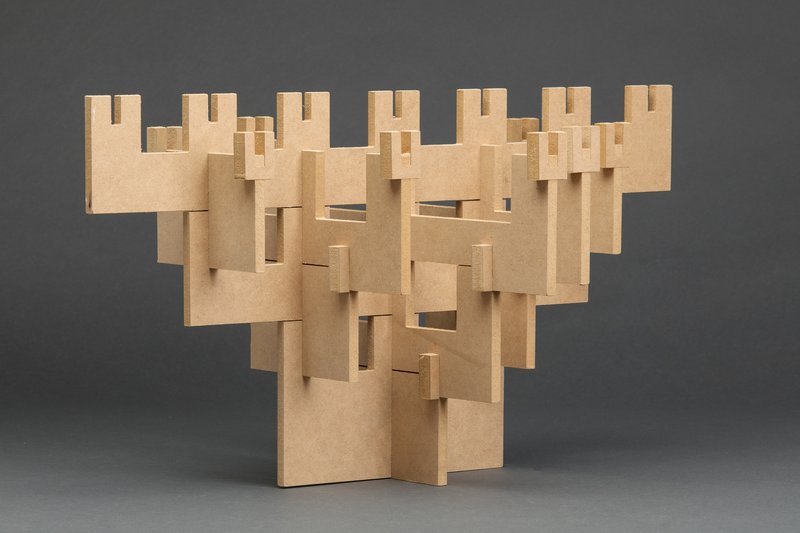 Cardboard study model showing interlocking vertical planes with notched apertures on grey backdrop