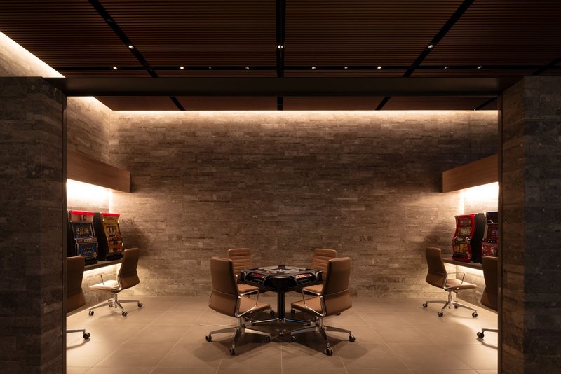 Game room with stone wall, concealed cove lighting, and poker table flanked by concrete columns
