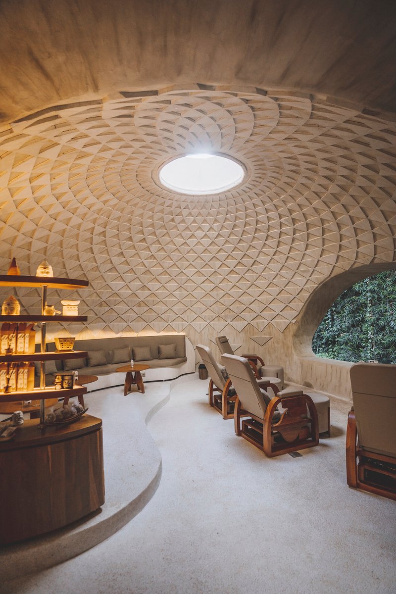 Circular interior space with a patterned timber dome ceiling and central oculus above a curved seating area