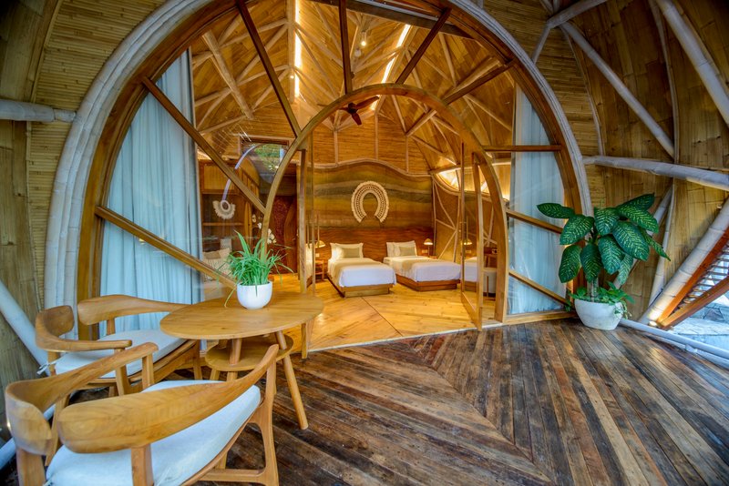Interior view through arched timber portal into sleeping quarters with exposed wood beams and vaulted ceiling