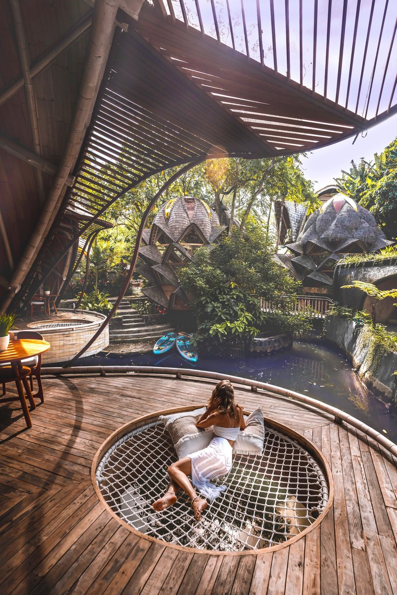 Deck with circular mesh net opening overlooking pond under slatted bamboo canopy