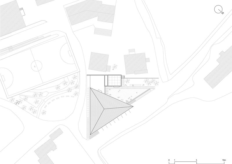 Site plan drawing showing a triangular building footprint with adjacent structures and landscaping
