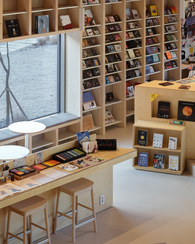 Plywood bookshelf wall with window seat overlooking a winter landscape outside