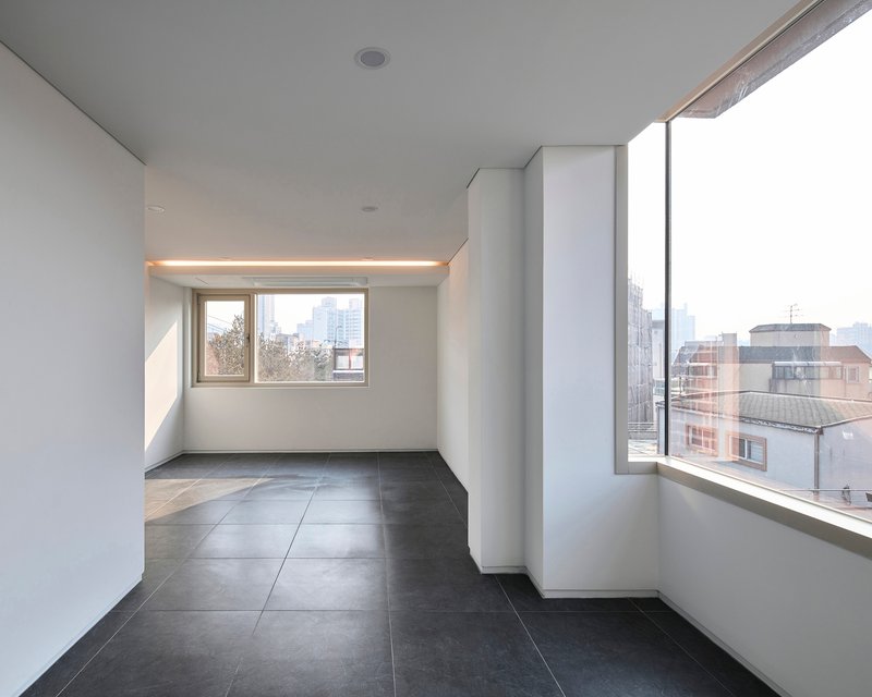 Interior corner with angled window walls and integrated linear lighting above the smaller opening