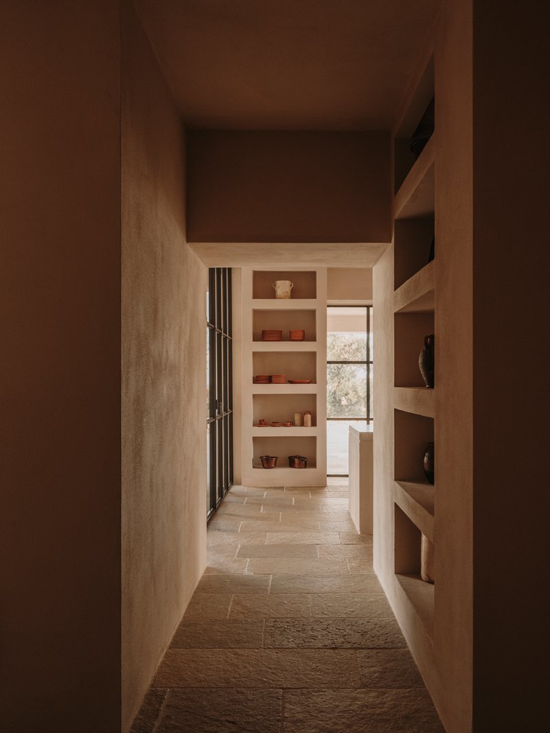 Narrow corridor framed by built-in timber shelving with soft afternoon light filtering through