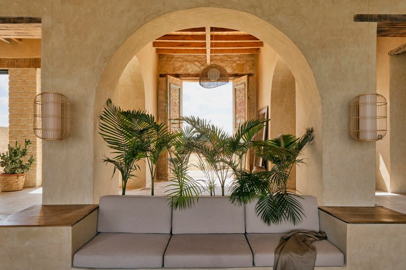 Layered arches framing a seating area with palm plants and woven wall sconces